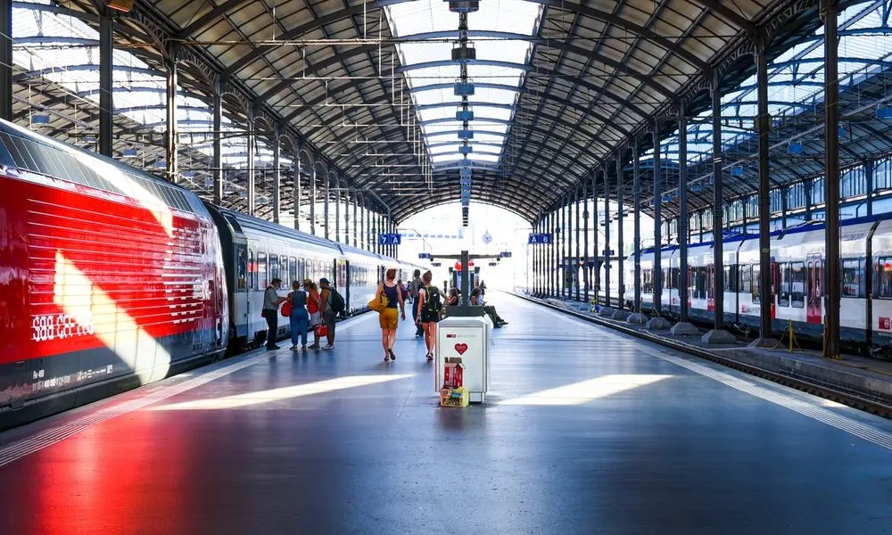 Nástupište železničnej stanice s vlakmi a cestujúcimi